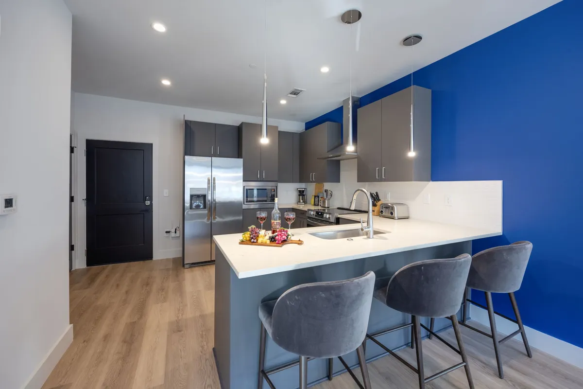 The hero image showcases a vibrant, contemporary kitchen with a spacious island, sleek appliances, colorful accent wall, and inviting bar stools, all designed for both casual meals and entertaining. The atmosphere is lively and stylish, perfect for gathering with friends or family.